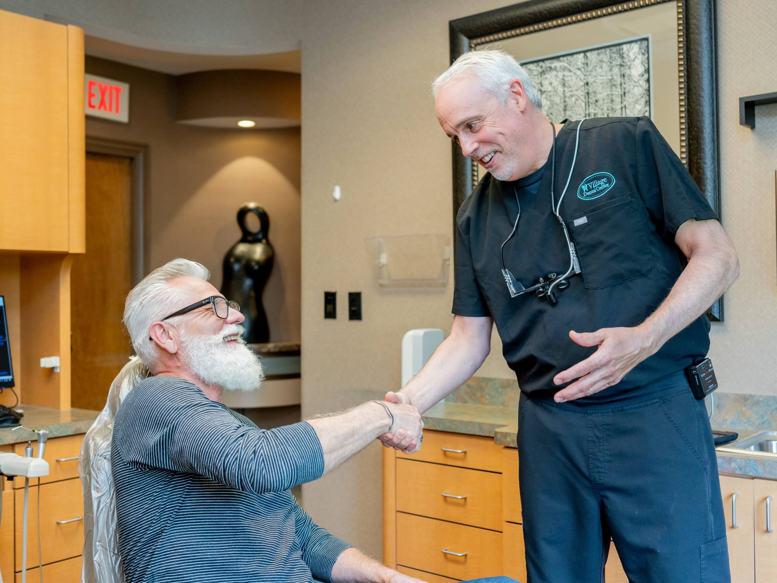 Dr. Kaplan of Village Dental Center in Lake Zurich talking to a male patient seated in a dental chair